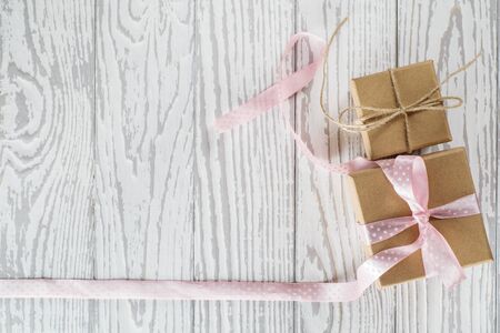 Two craft cardboard  gift boxes on a white wooden background. Gift kraft boxes with pink ribbon bow and rope.の写真素材