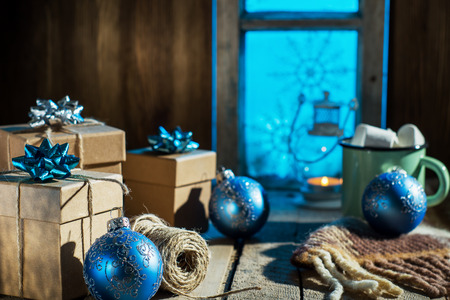 Christmas presents on old wooden table against the background of the old snow-covered window in vintage style. Rustic Christmas decoration. Packing of gifts.の写真素材
