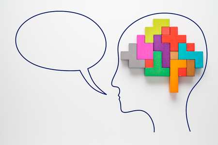 Head with colourful shapes of abstract brain with speech bubble. Human brain is made of multi-colored wooden blocks. Creative business concept. の写真素材