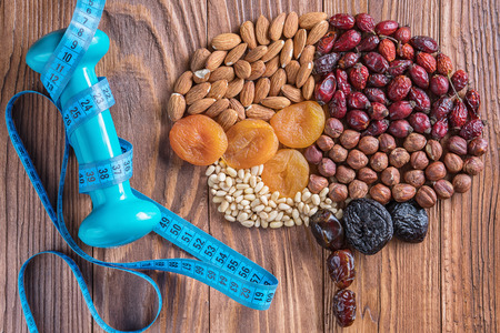Human brain is made of dried apricots and nuts with measuring tape and dumbbell on a wooden table. Brain made of a nuts and dried apricots. Concept of healthy food and healthy lifestyle. の写真素材