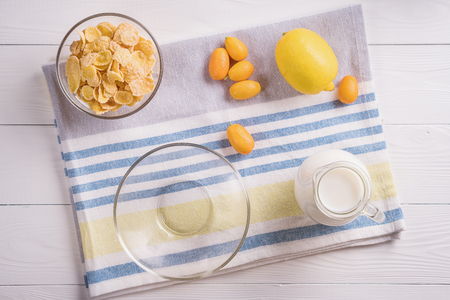 Bowl with corn flakes, jug of milk and empty bowl for prepared delicious breakfast.The concept of healthy breakfast, corn flakes with milk and fruit on wooden table, top view, flat lay. の写真素材