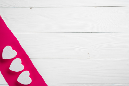 Decorative white wooden hearts on crimson paper and on the wooden background. Greeting card template for wedding or Valentines day. Wooden Background for design to Valentine's Day. の写真素材