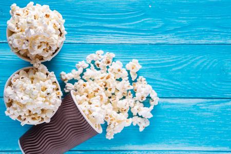 Popcorn in brown paper cups on blue wooden background with copy space, top view, flat lay.の写真素材