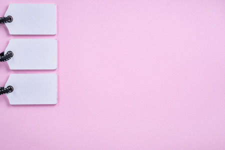 Empty white tags in a row on pink background. Top view. Mock up sample.