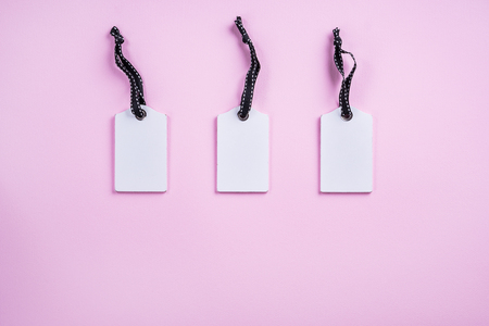Empty white tags in a row on pink background. Top view.の写真素材