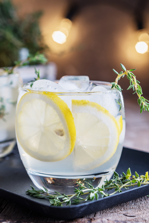 Lemon cocktail with thyme and ice on dark rustic background, close-up.の写真素材