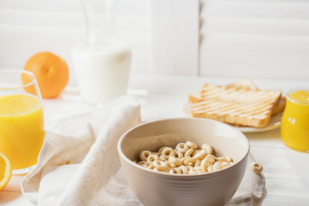 Whole Grain Cereal rings, milk, honey and orange juice on the white table.の写真素材