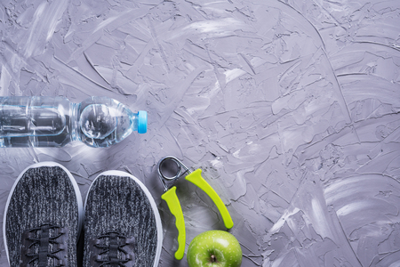 Sport shoes, bottle of water, apple and yoga mat with copy space on gray background.の写真素材