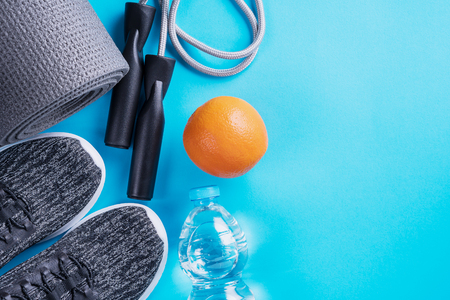 Sport shoes, bottle of water, apple and yoga mat with copy space on blue background.の写真素材