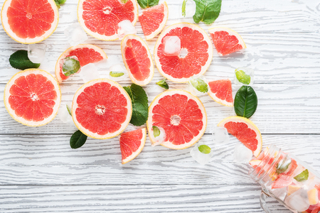 Detox water with grapefruit, mint and ice in mason jar on white wooden table.の写真素材