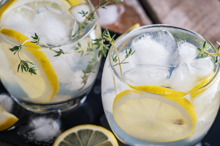 Lemon cocktail with thyme and ice on dark rustic background, close-up.の写真素材