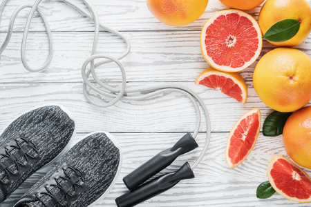 Fresh grapefruits and grapefruit juice and rope on rustic white wooden table, fitness accessories.の写真素材