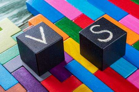 Letters VS on colorful wooden background with copy space. The concept of making choice. Versus concept. Black cubes with letters VS.の写真素材