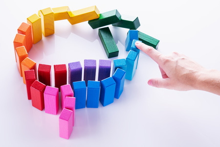 Brain disorder concept. The hand stops the disease of the brain. Human brain is made of multi-colored wooden blocks on white background.の写真素材
