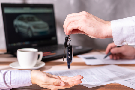 Car buyer are taking car keys from car owners. Buy, sell or rent concept.の写真素材