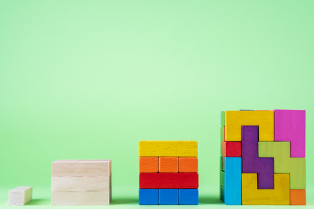 Growing graph from wooden cubes on green background. The concept of financial growth,  progress, development. Cubes of wooden multi-colored blocks.の写真素材