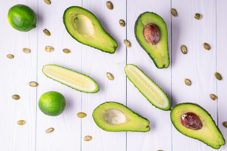 Avocado, cucumber, lime, pumpkin seeds on a white wooden table, healthy food. Healthy lifestyle concept, diet. Top view, copy space.の写真素材