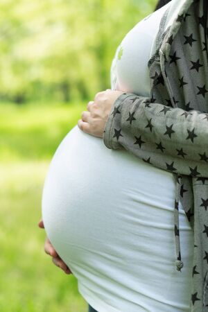 Young pregnant woman in the park. Happy pregnant woman stroking her belly. Woman at 39 weeks gestation (9 month).の写真素材