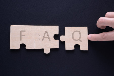 Hand attaches the missing piece of the puzzle. FAQ word on wooden cubes.の写真素材