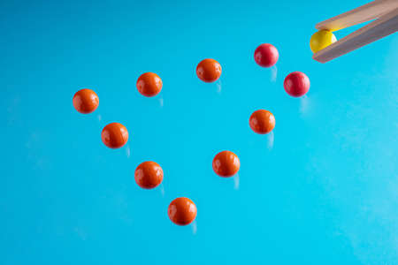 Arrow of red spheres and a yellow one on top of it on blue background. Leadership, success and uniqueness concept.の写真素材