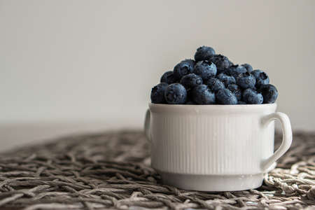 Water drops on ripe blueberries in small white dish on gray background.の写真素材