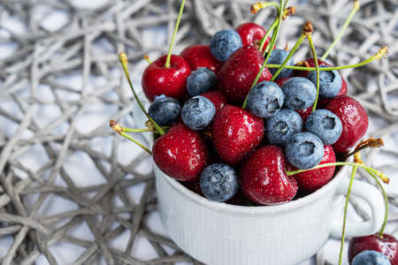 Ripe organic cherries and blueberries on gray background with copy space. Water drops on ripe juicy cherriesの写真素材