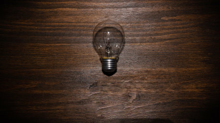 Light bulb is off. Energy concept with light bulb on brown wooden background with copy spaceの写真素材