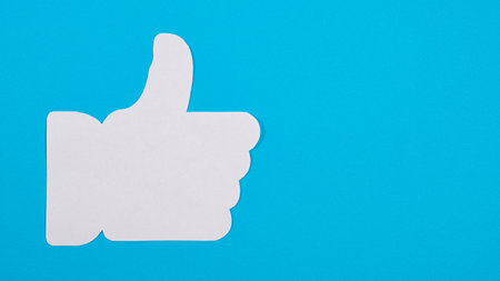 White thumb up on blue background, like symbol. Hand like with copy spaceの写真素材