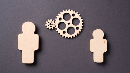 Two gears rotate between two wooden silhouettes of people Concept of teamwork, gear systemの写真素材