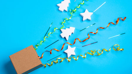 Gift box with scattered xmas decorations, confetti, Christmas tree, stars with copy space on blue background. christmas backgroundの写真素材