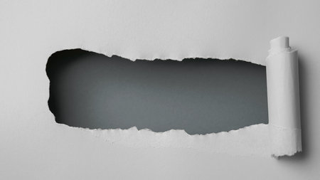 Gray paper is torn over dark gray background for message. Photo of torn gray paper over dark gray background with copy space, top viewの写真素材