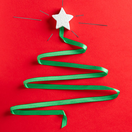 Christmas tree made of green ribbon with a burning white star on the red paper background. Abstract christmas tree with white starの写真素材