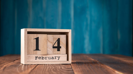 February 14 date on the wooden calendar with copy space on blue background. wooden cube calendarの写真素材