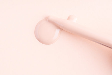 Drops of liquid make-up foundation texture with pipette on the nude color backgroundの写真素材
