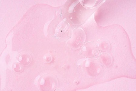 Macro shot of serum flows from pipette on pink background.の写真素材