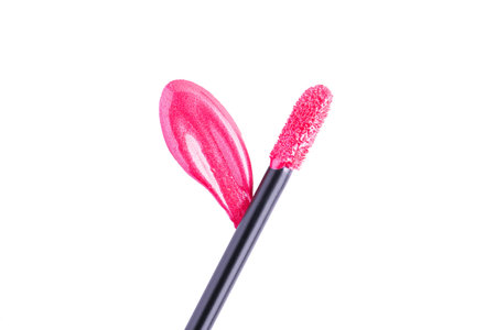 Pink shiny liquid lipstick and applicator isolated on white background. Swatch of deep pink lip gloss. Top view, flat lay, copy spaceの写真素材