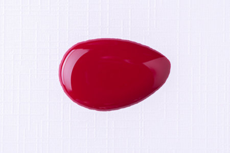 Splattered red nail polish or paint on white background. Splash of dark red nail polish. Top viewの写真素材