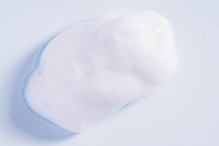 Foam texture on blue background. Soap, shampoo, mousse, shower gel foam, soap suds. Drop of bath foam. Macroの写真素材