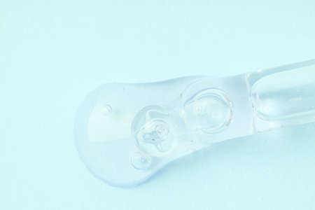 Macro shot of serum flows from dropper on blue background.の写真素材