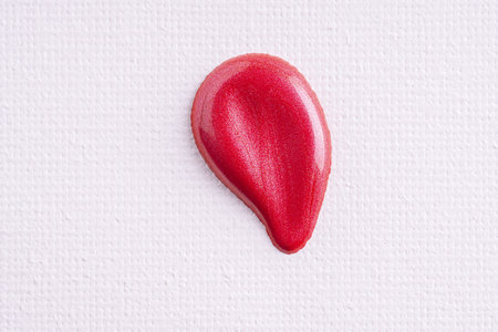 Swatches of dark shimmer red paint on white paper background. Deep red swatch of lip gloss, cosmetic product stroke or paint.の写真素材