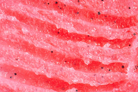 Red scrub background. Watermelon scrub texture, cosmetics skincare, body peeling. Flat lay, top view. Macroの写真素材