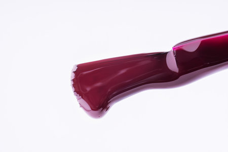 Red nail polish dripping from brushes nail on white background, macro shotの写真素材