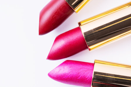 Three bright lipsticks on white background, macro. Moisturizing colorful shiny lipstick, close-up.の写真素材