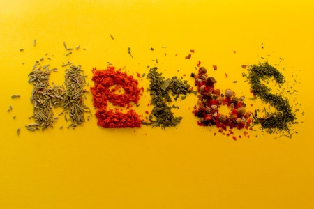 Assorted herbs spelling the word herbs, isolated on a yellow background の写真素材