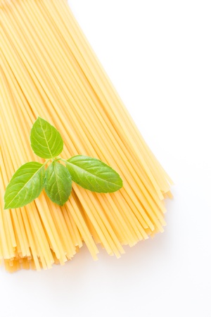 Spaghetti pasta with basil leaves on the white background の写真素材