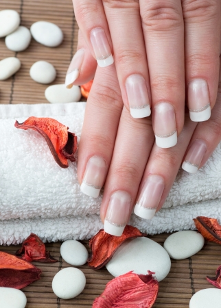 Woman hands with french manicure and flowers on wooden backgroundの写真素材