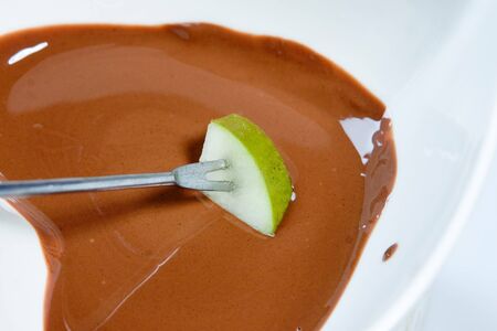 Piece of apple dip into melt chocolateの写真素材