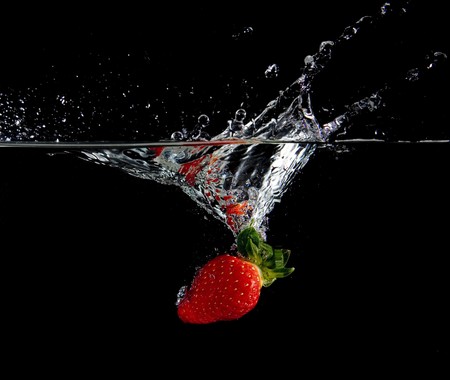 Strawberry in water with bubbles on black ground