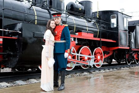 Young coupe in oldfashion dresses infront of old engine