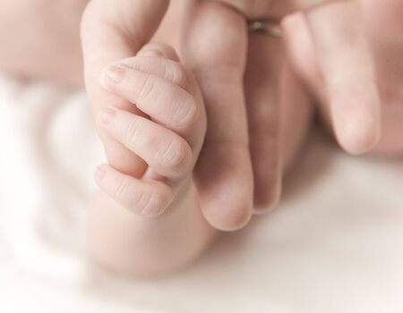 newborn baby hand holding mother's fingerの写真素材